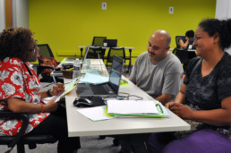 A volunteer tax preparer happily assists a family