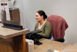 A smiling office assistant helps a customer online